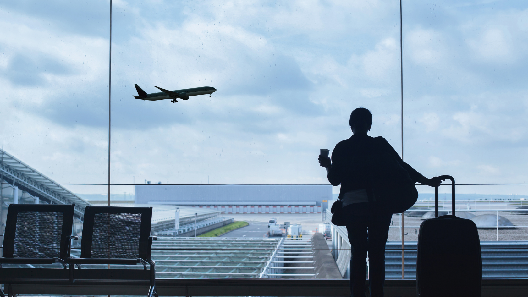 A person looking out an airport window at an airplane