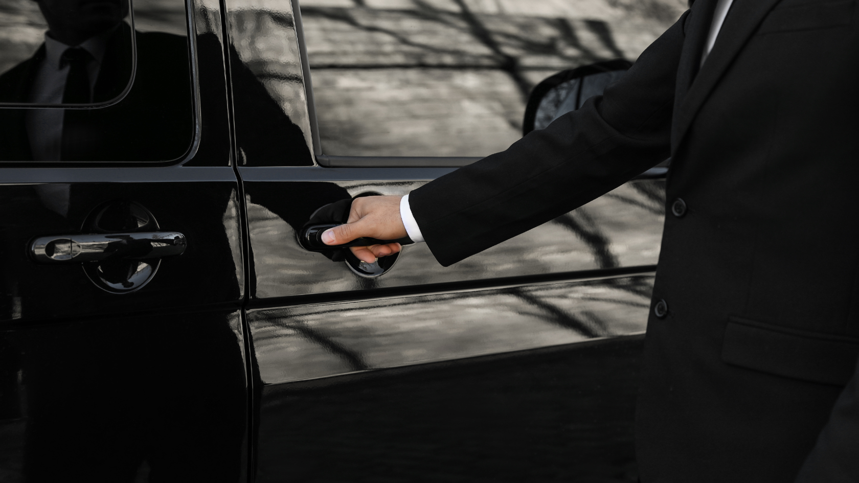 A man in a suit is opening the door of a car