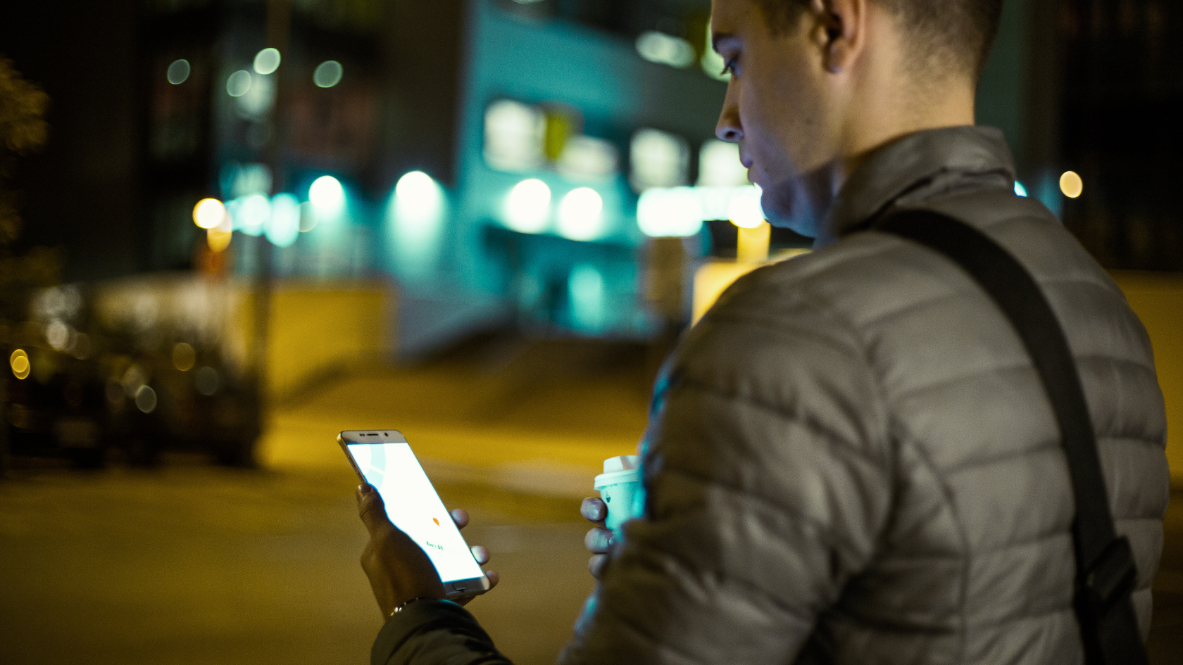 A man standing on a street holding a cell phone