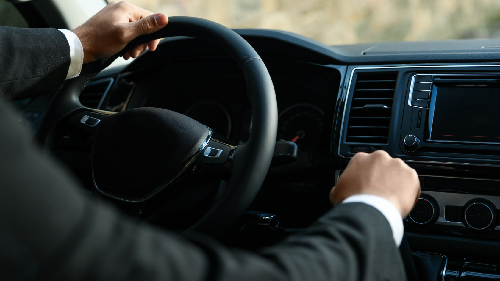 A man in a suit driving a car