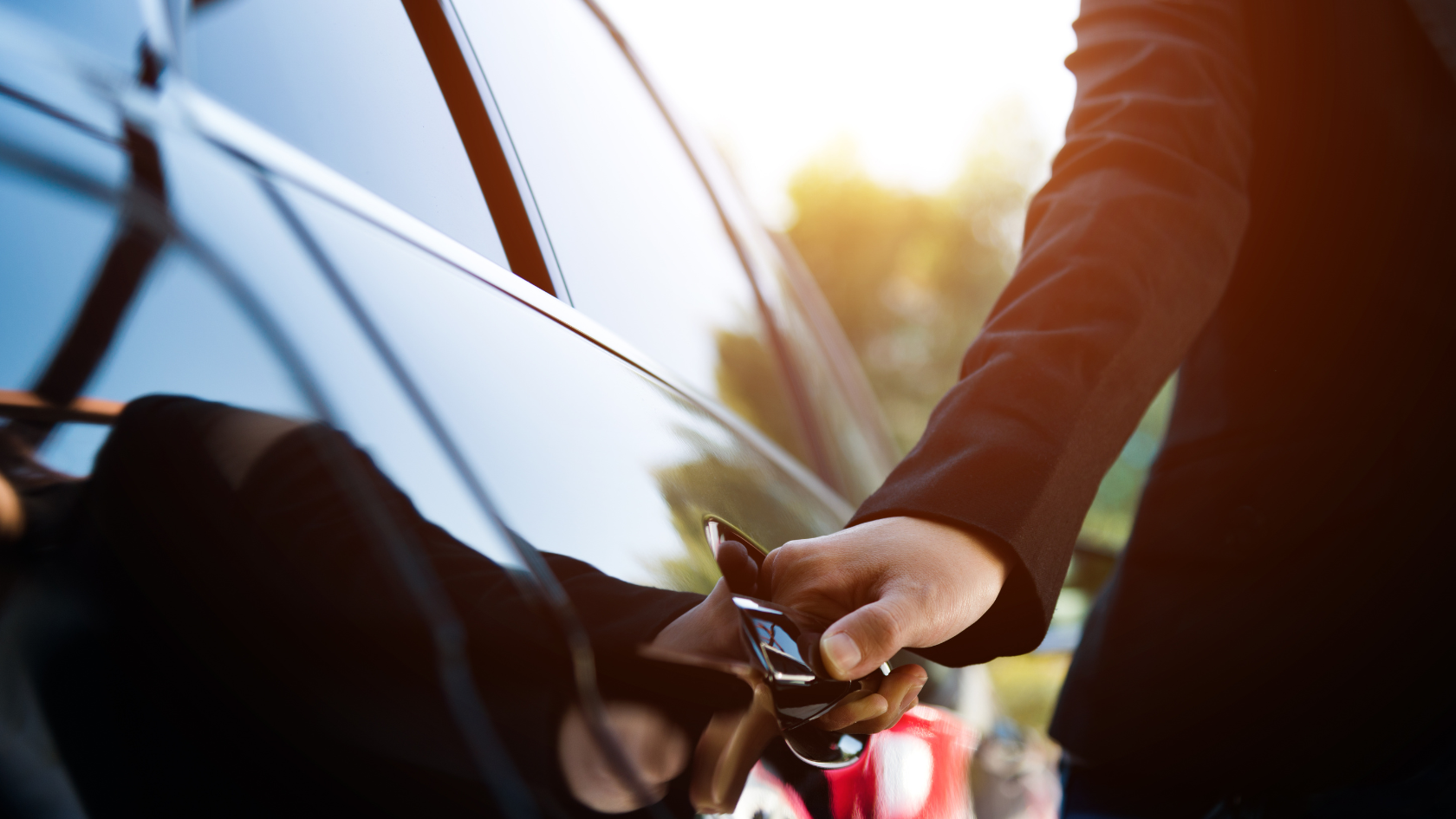 A man in a suit is opening the door of a car