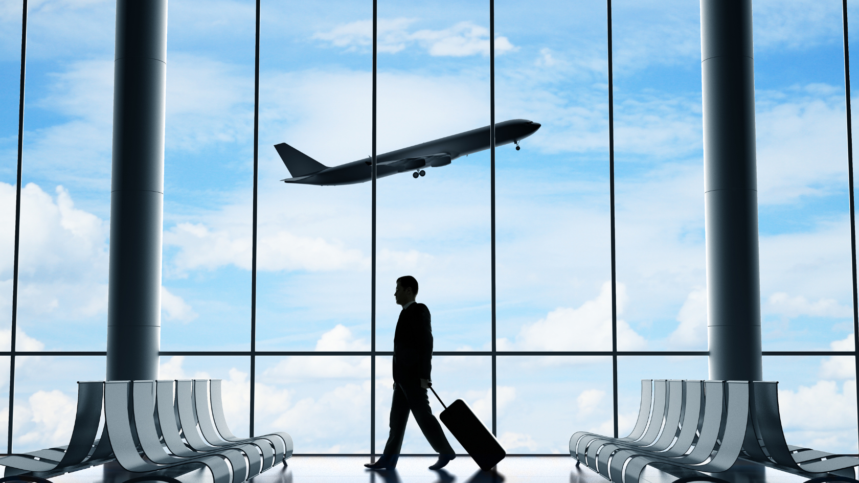 A man walking through an airport with a suitcase